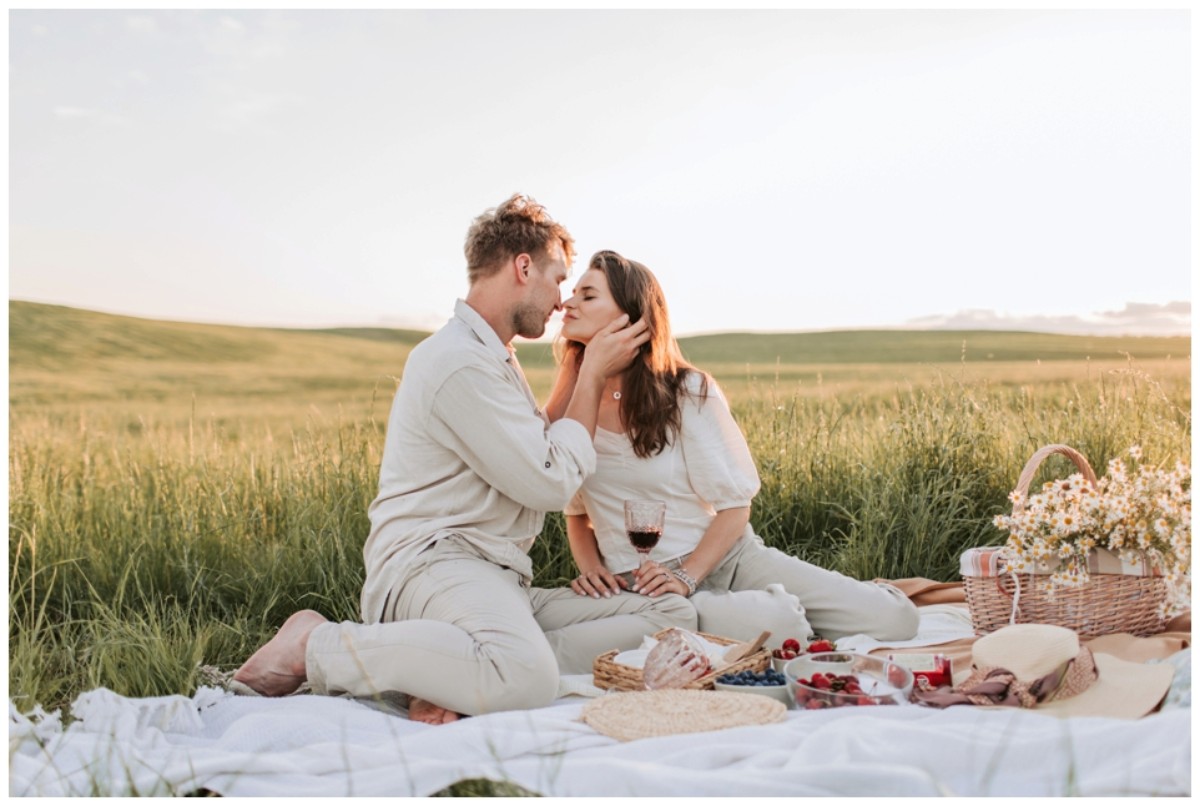 Un couple amoureux partage un moment tendre lors d’un pique-nique champêtre au coucher du soleil, célébrant leurs noces de cuir – symbole des 2 ans de mariage.